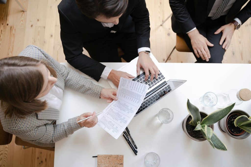 Overhead view of colleagues collaborating at a desk with laptop and documents in a business meeting.